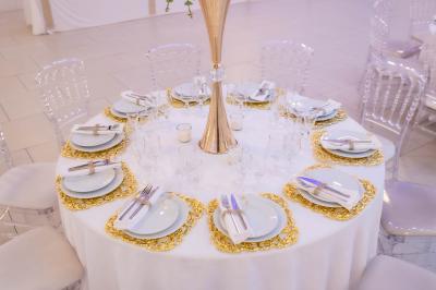 Deux fauteuils dorés ornés de motifs, entourés de fleurs blanches et roses, devant un rideau beige.