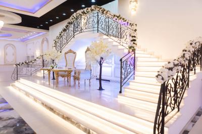 Deux fauteuils dorés ornés de motifs, entourés de fleurs blanches et roses, devant un rideau beige.