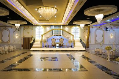 Deux fauteuils dorés ornés de motifs, entourés de fleurs blanches et roses, devant un rideau beige.