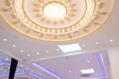 Deux fauteuils dorés ornés de motifs, entourés de fleurs blanches et roses, devant un rideau beige.