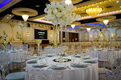 Deux fauteuils dorés ornés de motifs, entourés de fleurs blanches et roses, devant un rideau beige.