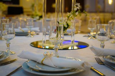 Deux fauteuils dorés ornés de motifs, entourés de fleurs blanches et roses, devant un rideau beige.