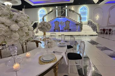 Deux fauteuils dorés ornés de motifs, entourés de fleurs blanches et roses, devant un rideau beige.