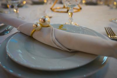 Deux fauteuils dorés ornés de motifs, entourés de fleurs blanches et roses, devant un rideau beige.