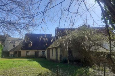 Salle rustique avec tables et chaises en bois, sol en carrelage ancien, poutres apparentes et lumière naturelle.