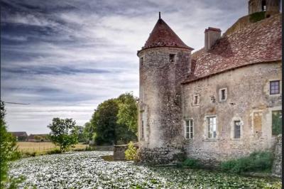 Salle rustique avec tables et chaises en bois, sol en carrelage ancien, poutres apparentes et lumière naturelle.