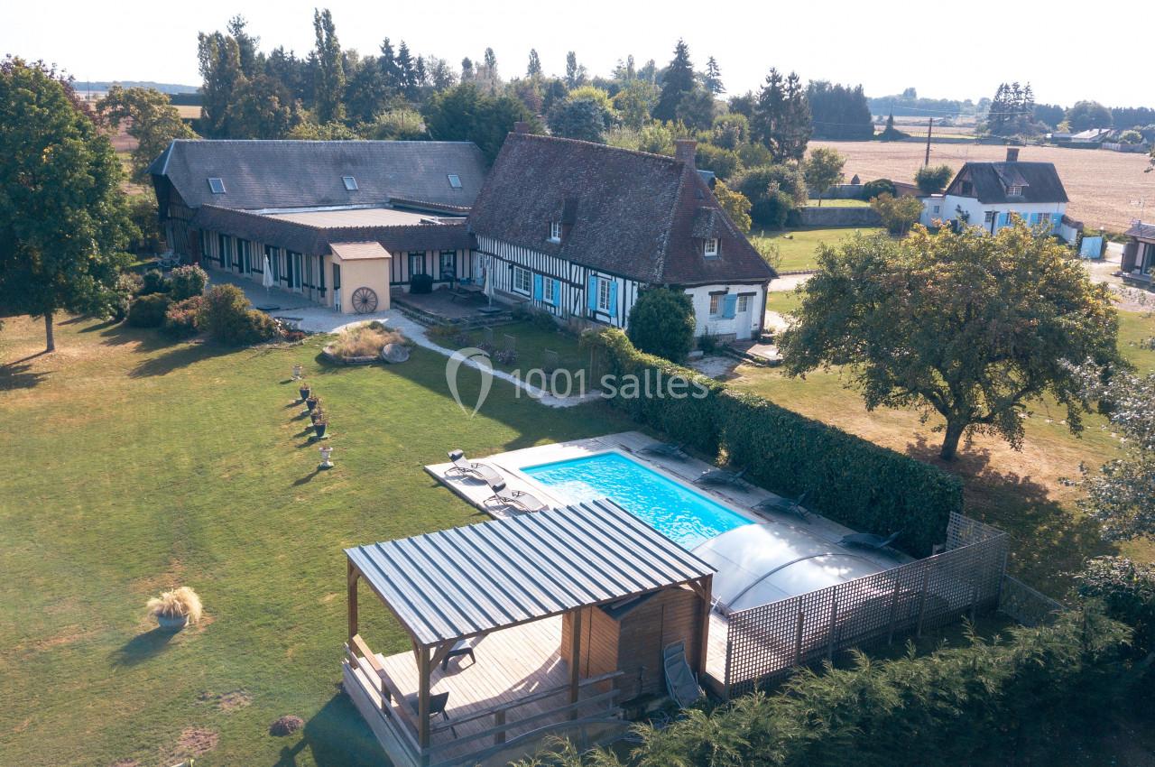 Vue aérienne d'une maison traditionnelle avec piscine, terrasse couverte et grand jardin arboré en campagne.
