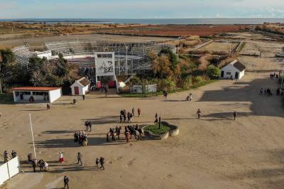 Grande salle vide avec un sol en pierre, plafond en bois avec poutres apparentes et lustres suspendus, décorée de plantes.