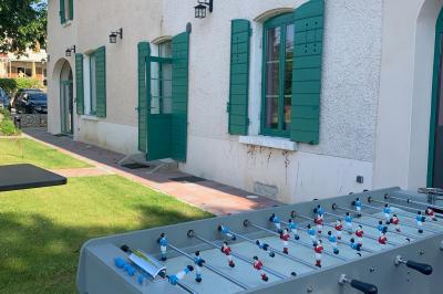 Salle de réunion lumineuse avec murs roses, tables modernes, miroir doré et écran mural.