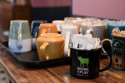 Salle de réunion lumineuse avec murs roses, tables modernes, miroir doré et écran mural.
