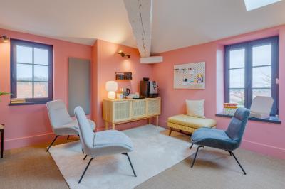 Salle de réunion lumineuse avec murs roses, tables modernes, miroir doré et écran mural.