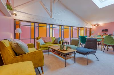 Salle de réunion lumineuse avec murs roses, tables modernes, miroir doré et écran mural.