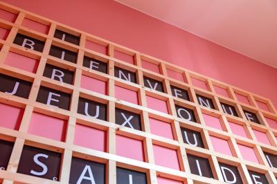 Salle de réunion lumineuse avec murs roses, tables modernes, miroir doré et écran mural.