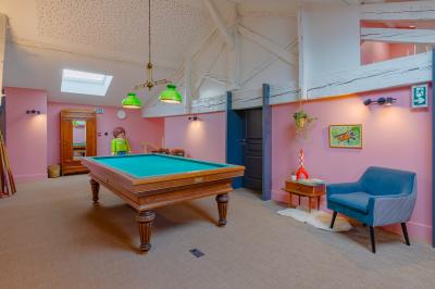 Salle de réunion lumineuse avec murs roses, tables modernes, miroir doré et écran mural.