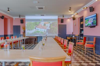 Salle de réunion lumineuse avec murs roses, tables modernes, miroir doré et écran mural.