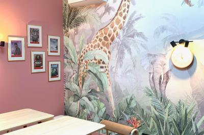 Salle de réunion lumineuse avec murs roses, tables modernes, miroir doré et écran mural.