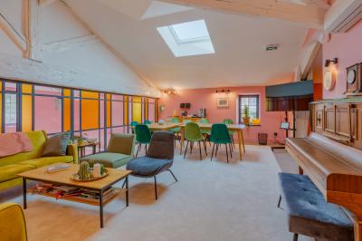 Salle de réunion lumineuse avec murs roses, tables modernes, miroir doré et écran mural.