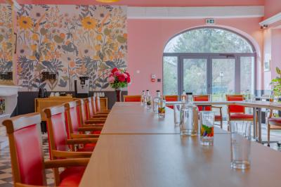 Salle de réunion lumineuse avec murs roses, tables modernes, miroir doré et écran mural.