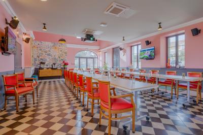 Salle de réunion lumineuse avec murs roses, tables modernes, miroir doré et écran mural.