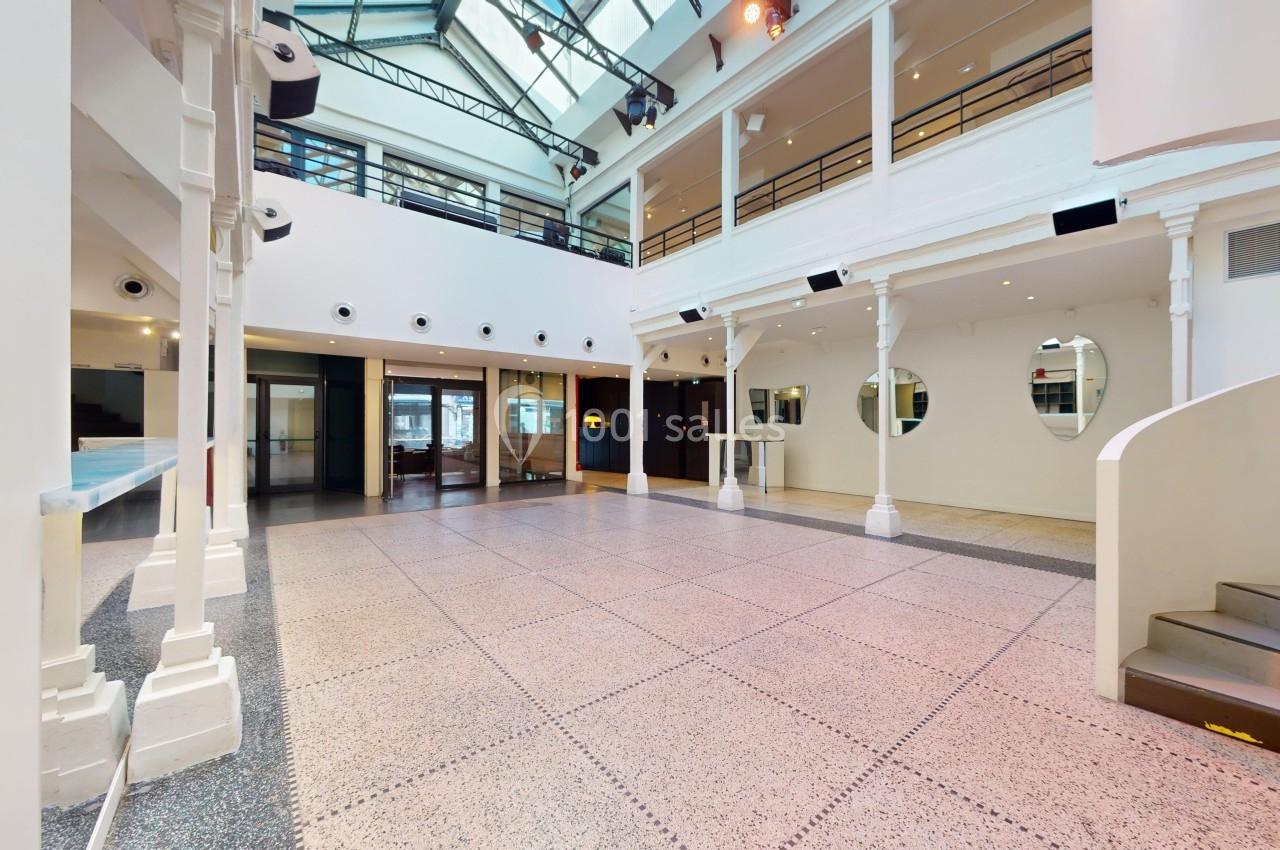 Vue intérieure d'un espace lumineux avec mezzanine, grandes baies vitrées, escalier et sol en carrelage clair.