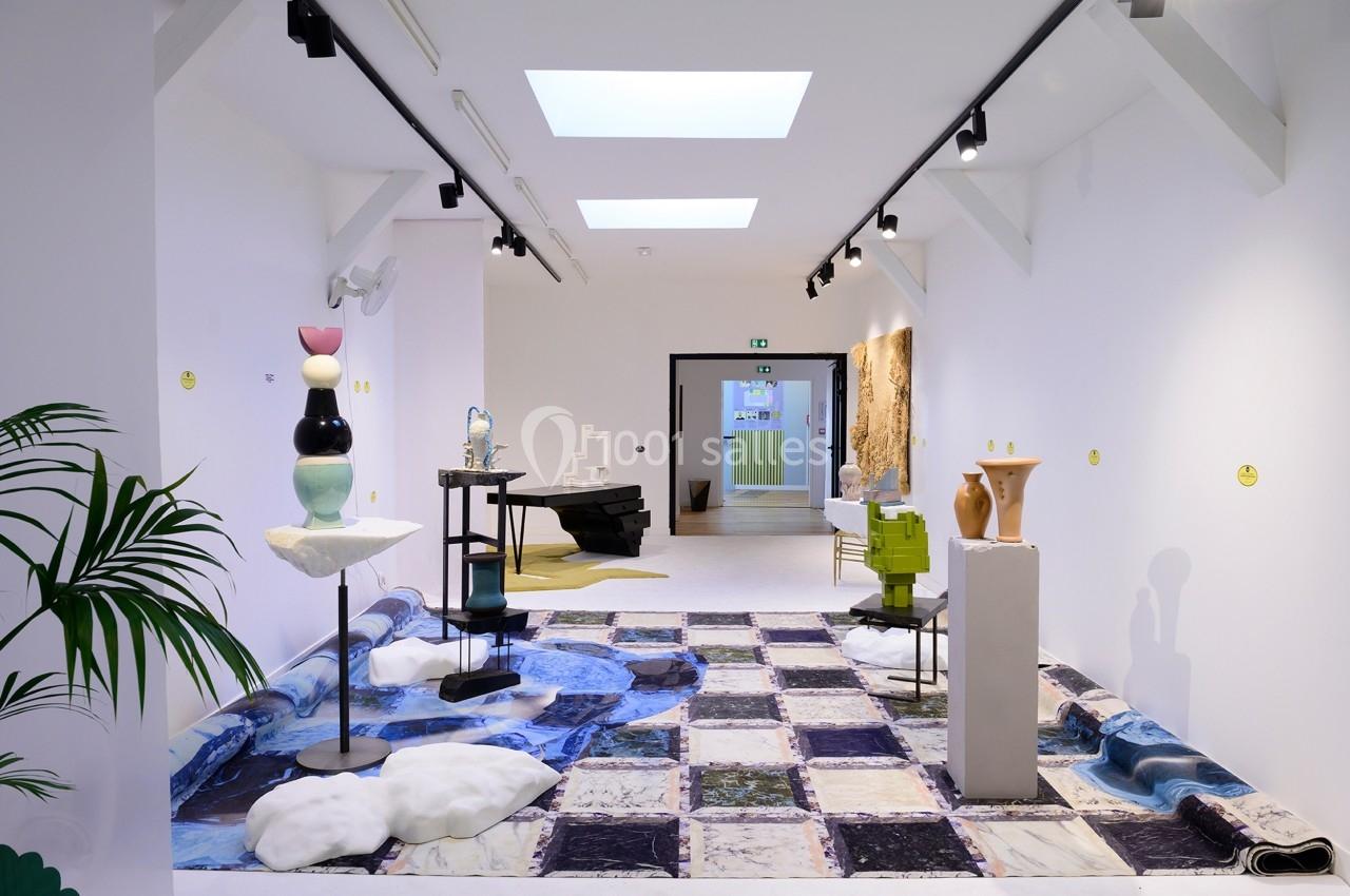 Vue d'une galerie d'art moderne avec sculptures et installations sur un sol à motifs marbrés.