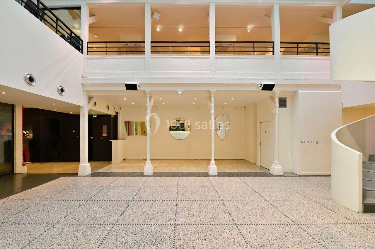 Vue d'un espace intérieur lumineux avec un sol en terrazzo, des murs blancs et un escalier en colimaçon.