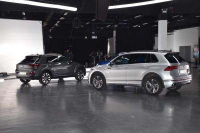 Des personnes discutent et prennent un verre autour de tables en bois devant un bâtiment industriel lors d'un événement.