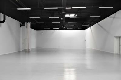 Des personnes discutent et prennent un verre autour de tables en bois devant un bâtiment industriel lors d'un événement.