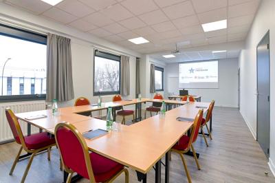 Des personnes discutent et prennent un verre autour de tables en bois devant un bâtiment industriel lors d'un événement.