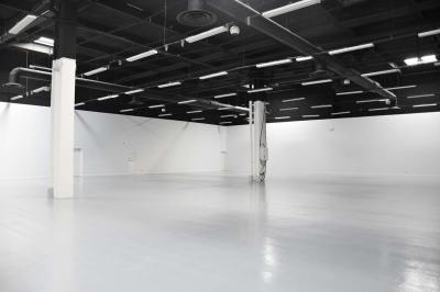 Des personnes discutent et prennent un verre autour de tables en bois devant un bâtiment industriel lors d'un événement.