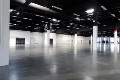 Des personnes discutent et prennent un verre autour de tables en bois devant un bâtiment industriel lors d'un événement.