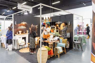 Des personnes discutent et prennent un verre autour de tables en bois devant un bâtiment industriel lors d'un événement.