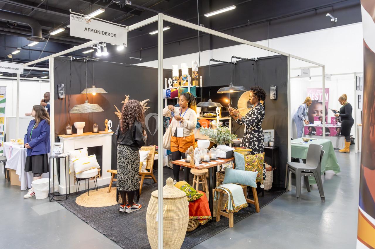 Stand d'exposition présentant des objets de décoration artisanaux avec plusieurs personnes en interaction.