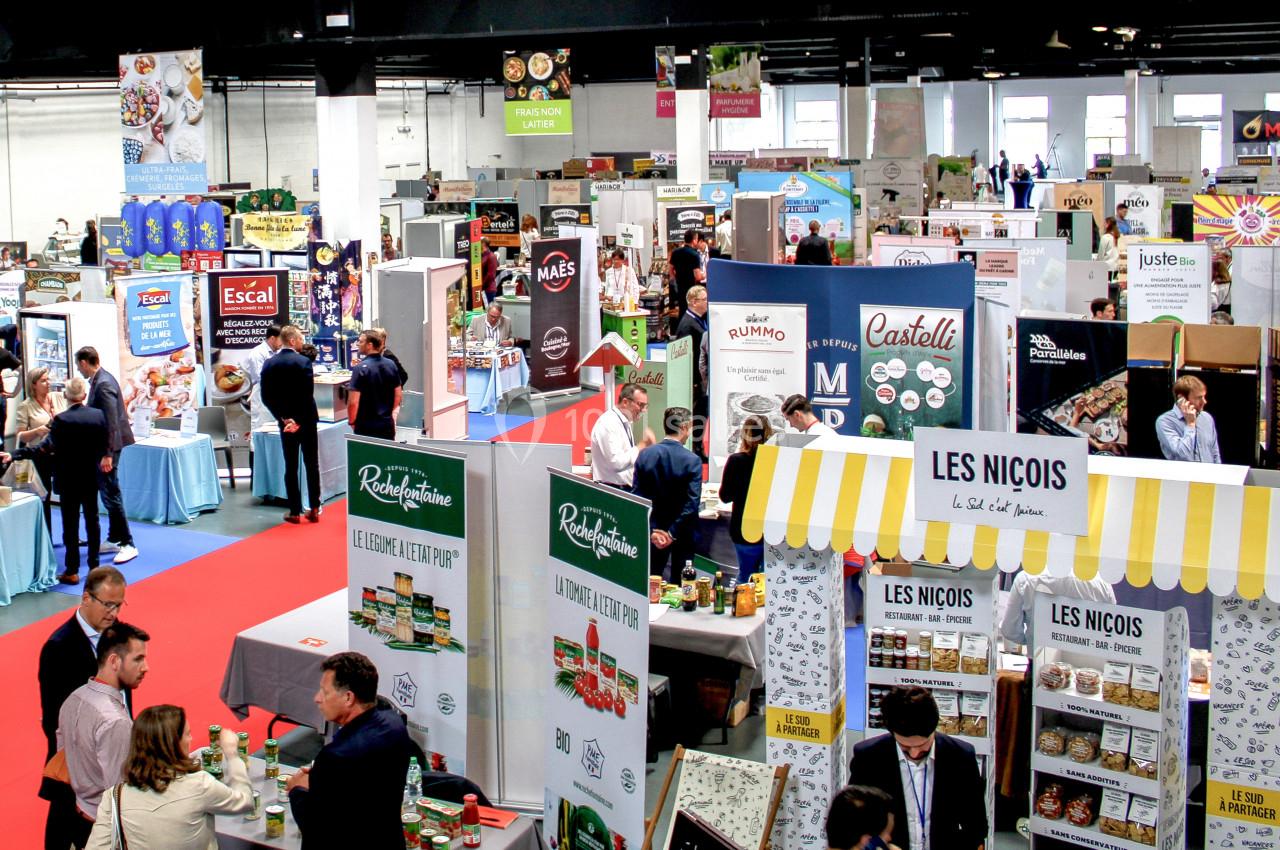 Vue d'un salon professionnel avec des stands exposant des produits alimentaires et des visiteurs circulant dans les allées.