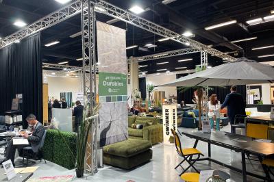 Des personnes discutent et prennent un verre autour de tables en bois devant un bâtiment industriel lors d'un événement.