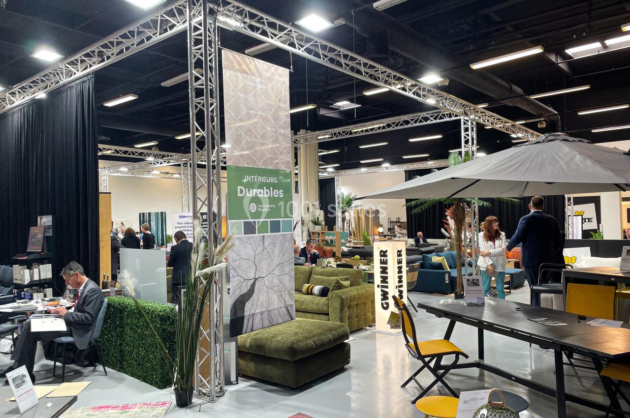 Salon d'exposition intérieur avec stands de meubles, décoration et visiteurs circulant entre les espaces aménagés.