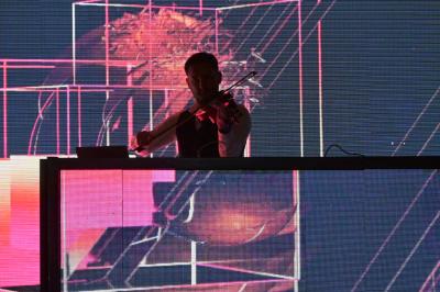 Personnes dansant et discutant dans une ambiance tamisée de boîte de nuit avec un écran lumineux en arrière-plan.