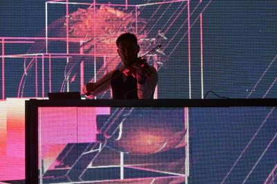 Personnes dansant et discutant dans une ambiance tamisée de boîte de nuit avec un écran lumineux en arrière-plan.