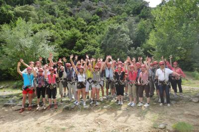 Tables de banquet en plein air avec nappes à carreaux rouges et blanches, disposées sous un arbre dans un cadre champêtre.
