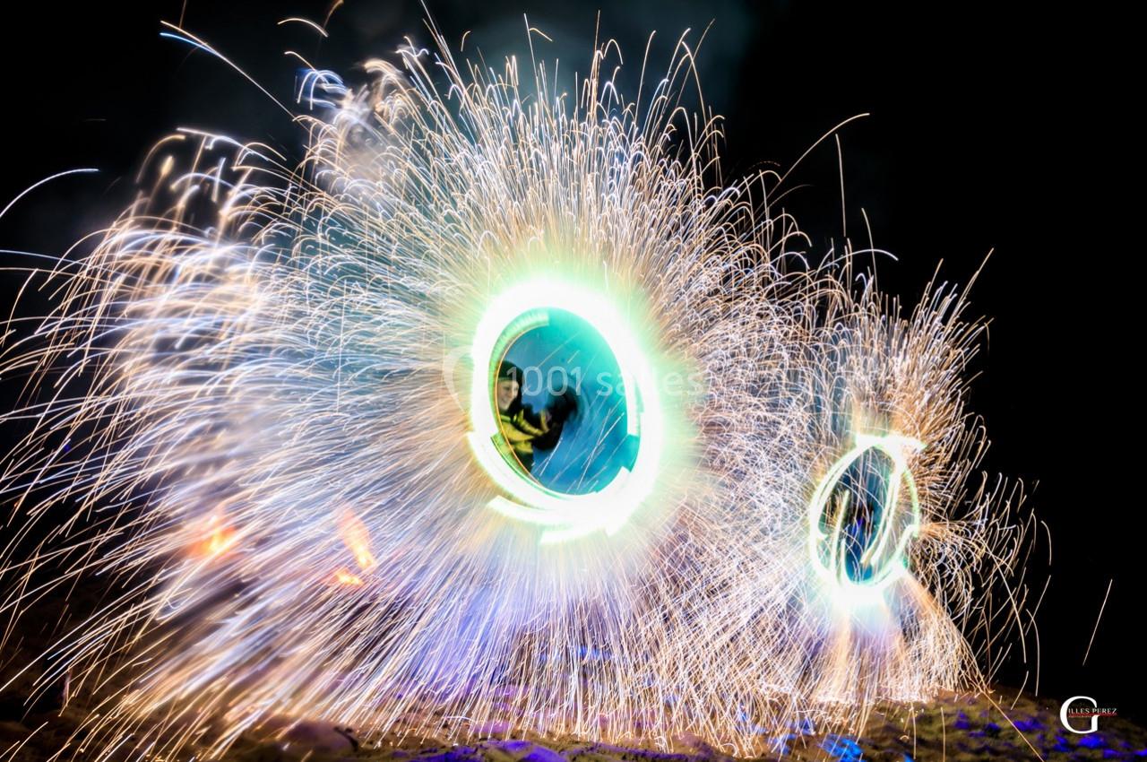 Deux personnes dans des cercles lumineux entourés d'étincelles dans un décor nocturne.