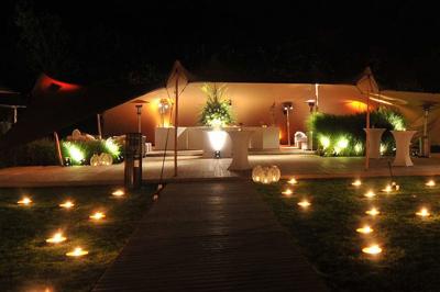 Tente transparente installée sur une plage, aménagée avec des chaises blanches et des plantes décoratives.
