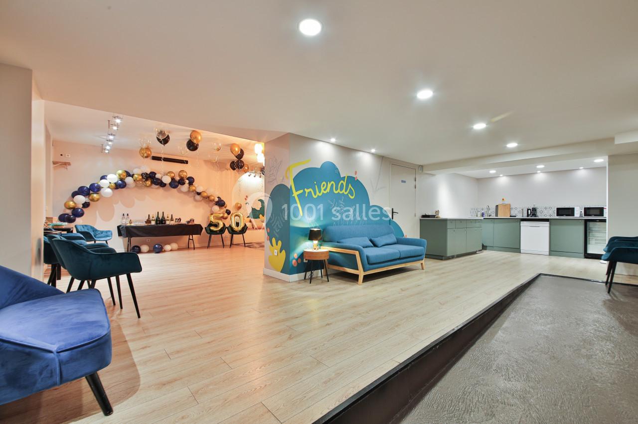 Salle lumineuse avec coin salon, cuisine équipée et décoration festive composée de ballons et d'une arche colorée.