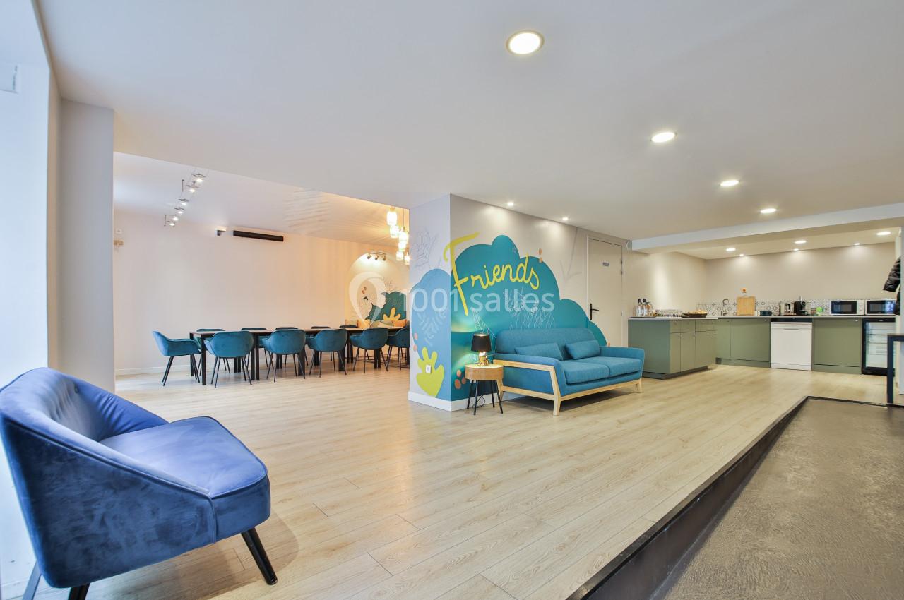 Salle lumineuse avec coin salon, table à manger, cuisine équipée et mur décoré d'une fresque colorée.