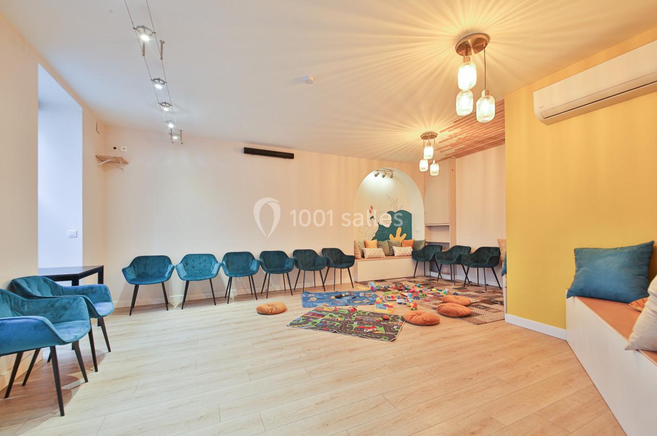 Salle lumineuse avec chaises disposées en cercle, tapis coloré au sol, coussins et décor mural illustré.