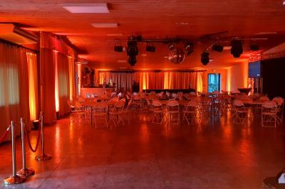 Espace intérieur en bois avec canapés, fauteuils, guirlande lumineuse et stand décoratif éclairé.