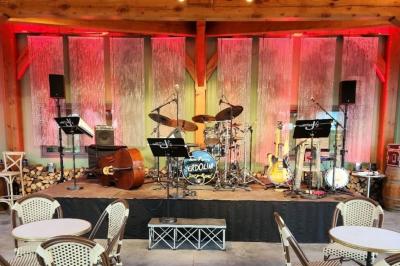 Espace intérieur en bois avec canapés, fauteuils, guirlande lumineuse et stand décoratif éclairé.