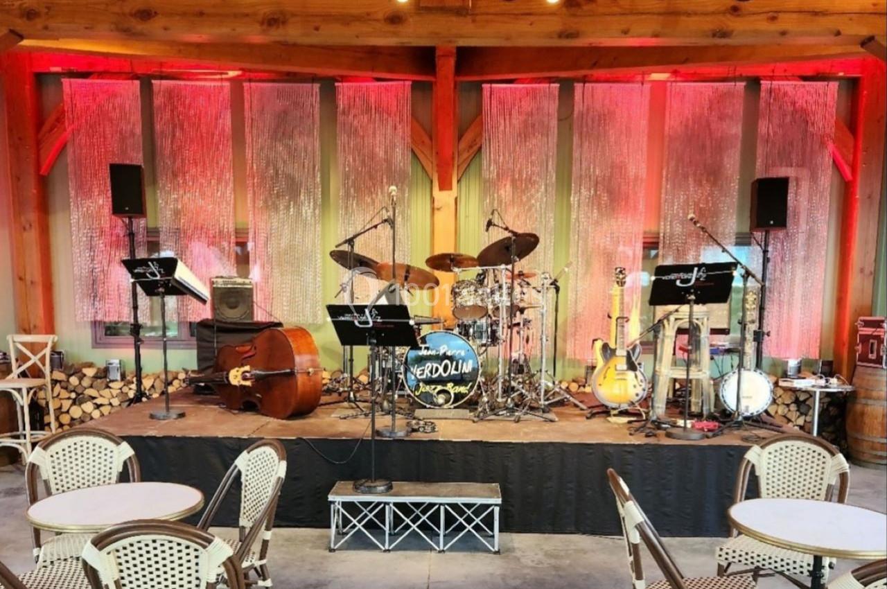 Scène de concert avec instruments de musique installés, dont une contrebasse, une batterie et des guitares, éclairée par des…