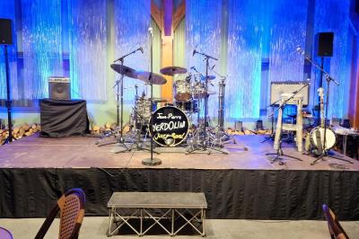 Espace intérieur en bois avec canapés, fauteuils, guirlande lumineuse et stand décoratif éclairé.