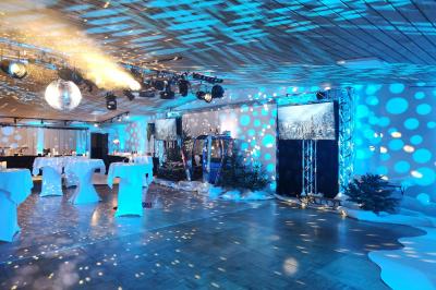 Espace intérieur en bois avec canapés, fauteuils, guirlande lumineuse et stand décoratif éclairé.