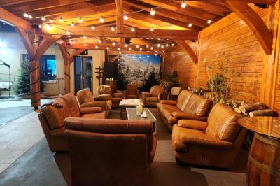 Espace intérieur en bois avec canapés, fauteuils, guirlande lumineuse et stand décoratif éclairé.